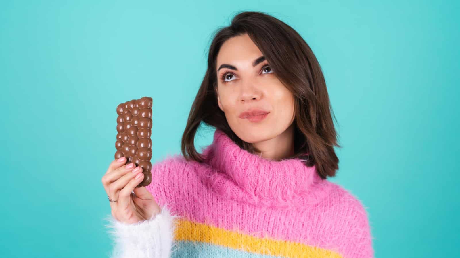 mujer-joven-sueter-multicolor-brillante-sobre-azul-disfruta-cada-pieza-deliciosa-barra-chocolate-leche-aireado (1)